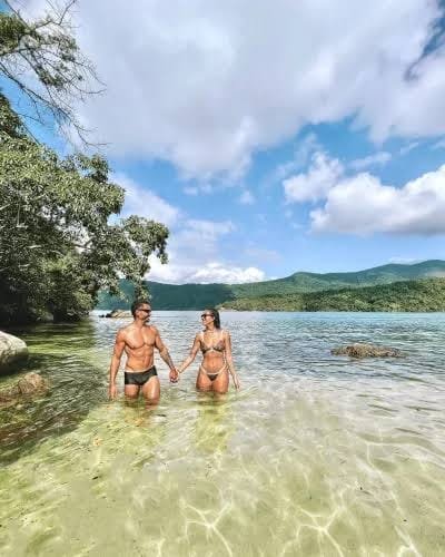 Casal em praia de águas transparentes